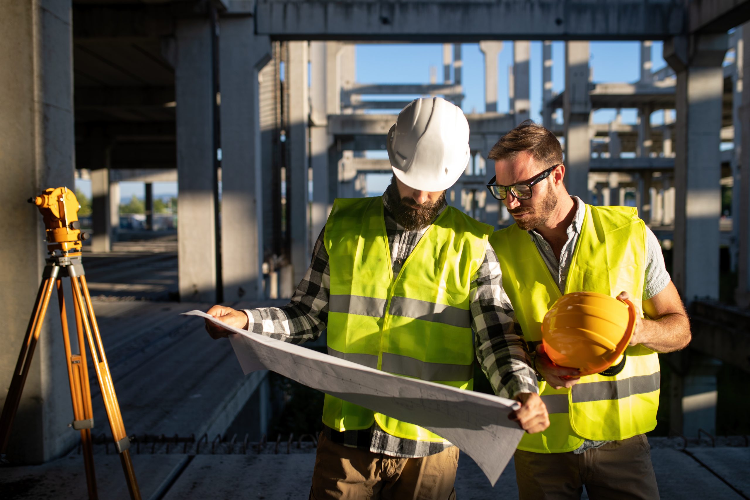 Business, building, teamwork and people concept. Group of engineer and architects in hardhats with blueprint on construction site